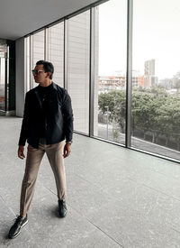 Full length of young man looking through window