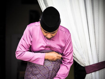 Midsection of man standing against pink wall