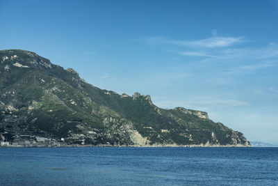 Scenic view of sea and mountains against blue sky