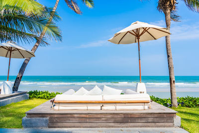 Lounge chairs by swimming pool by sea against sky