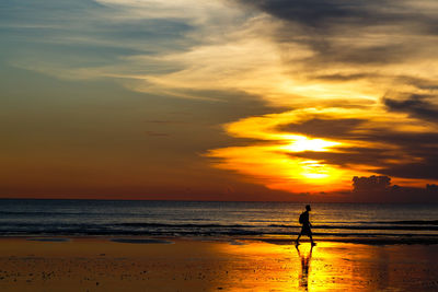 Silhouette man standing at beach during sunset