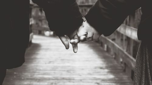 Close-up of man and woman holding hands on boardwalk
