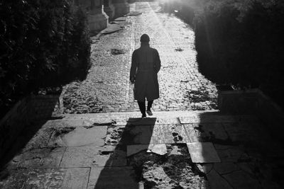 Rear view of man walking on footpath