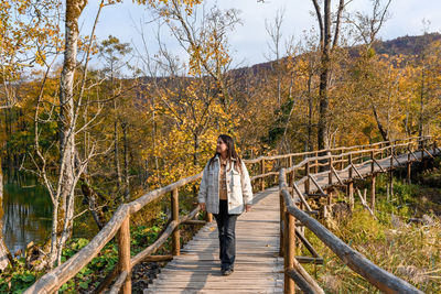 Girl on wooden footpath in plitvice lakes national park in croatia in autumn