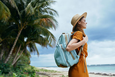 Woman looking away while standing on palm tree