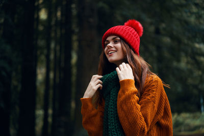 Young woman looking away in forest during winter