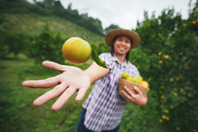 Woman throwing orange while standing at farm