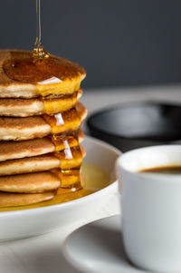 Close-up of honey falling on stacked pancakes at table