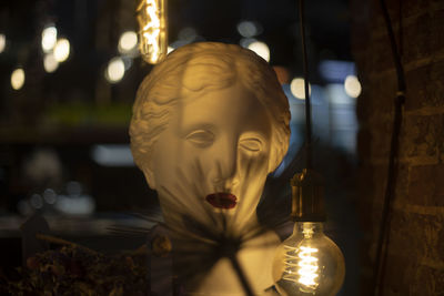 Greek sculpture. woman's head made of plaster. plaster statue. interior details. incandescent lamp.