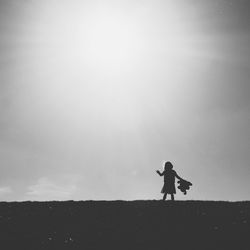 Man with umbrella on sand against sky