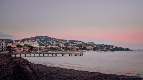 City by sea against clear sky during sunset