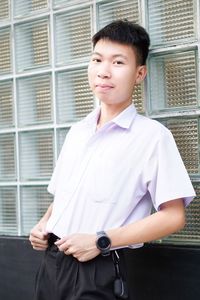 Portrait of young man standing against wall