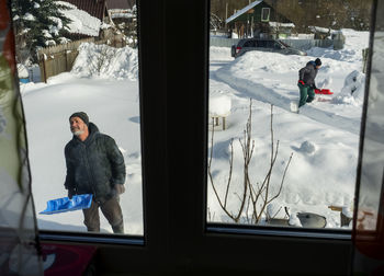 High angle view father and son cleaning snow while standing outdoors