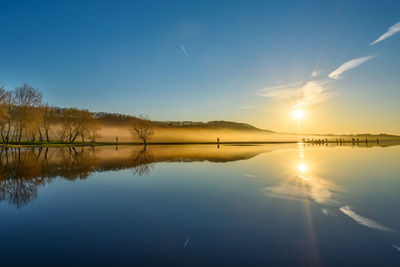 Scenic view of lake against sky at sunset
