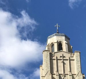 Church steeple with blue sky full of fluffy clouds in the background 