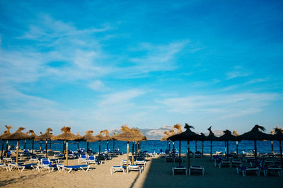 Lounge chairs on beach against blue sky