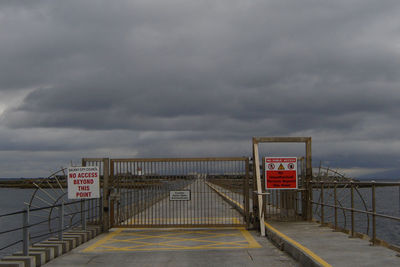 Closed gate on concrete road at ocean