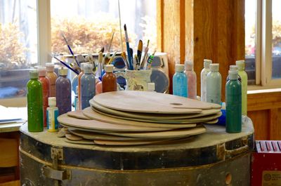 Colorful paint bottles with palette on drum at workshop