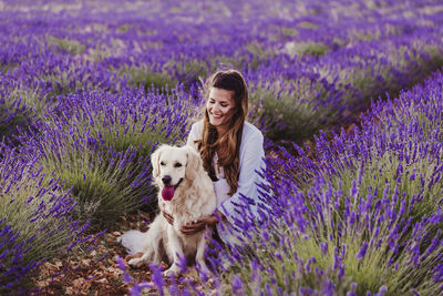 Woman with dog by purple flowering plants on land