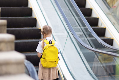 Rear view of people walking on escalator