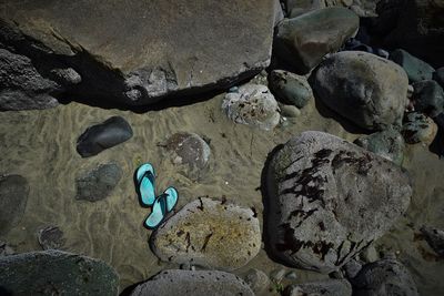 High angle view of flip-flops amidst rocks at beach