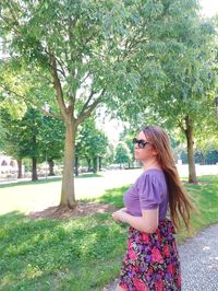 Young woman standing against trees