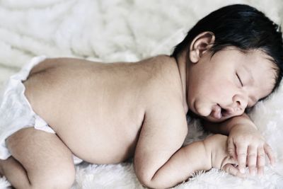 Baby boy sleeping on bed at home