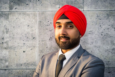 Close-up portrait of businessman wearing turban standing against wall