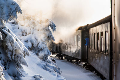 Train on snow covered railroad track against sky