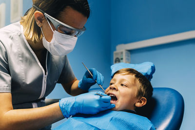 Dentist operating boy in medical clinic