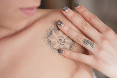 Flower tattoo on shoulder and g clef tattooed on finger