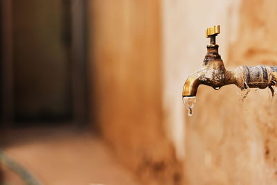 Close-up of old faucet against wall