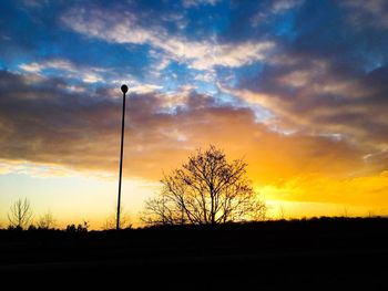 Low angle view of silhouette trees against dramatic sky