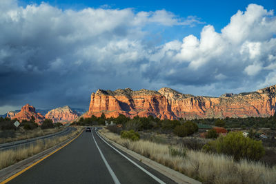 Road by rock formations against sky