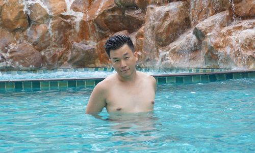 Portrait of shirtless man swimming in pool