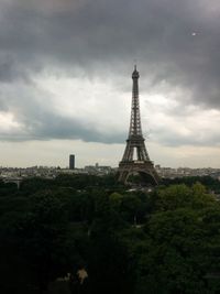 Tower in city against cloudy sky