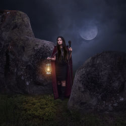 Young woman standing on rock at night