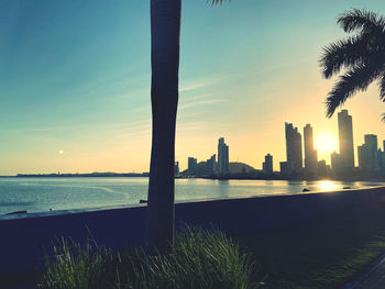 Sea and buildings against sky during sunset