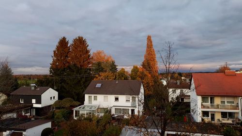 Houses amidst trees and buildings against sky