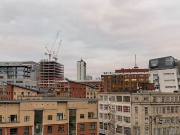 Buildings in city against cloudy sky