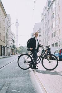 Full length of businessman with bicycle on road in city