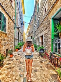 Rear view of woman walking on footpath amidst buildings