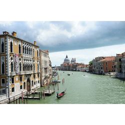 View of canal and buildings against cloudy sky