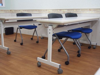 Empty chairs and tables on hardwood floor in a classroom