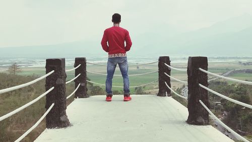 Rear view of man standing on wooden post