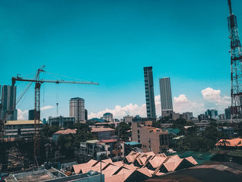 Construction site by buildings against blue sky