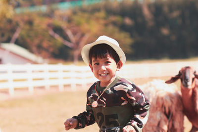 Portrait of smiling boy wearing hat standing outdoors at farm