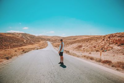 Rear view of man walking on road against sky