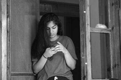 Beautiful young woman drinking from window at home