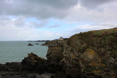 Scenic view of sea and cliff against sky